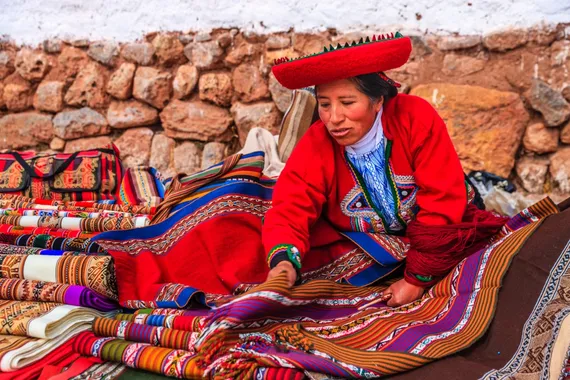 Mulher peruana vendendo artesanatos em ruínas incas no vale sagrado, Peru