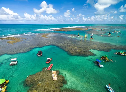 Barcos e banhistas nas águas cristalinas junto aos corais em Maragogi